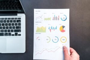 une main présente une page de graphiques à côté d'un ordinateur portable.