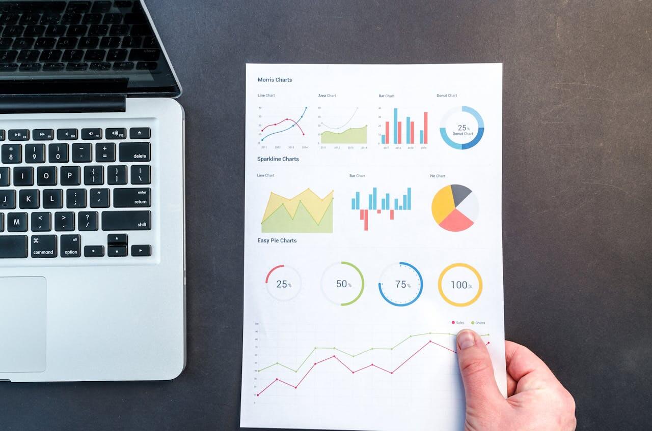 Répartition par tranches d'âge une main présente une page de graphiques à côté d'un ordinateur portable.
